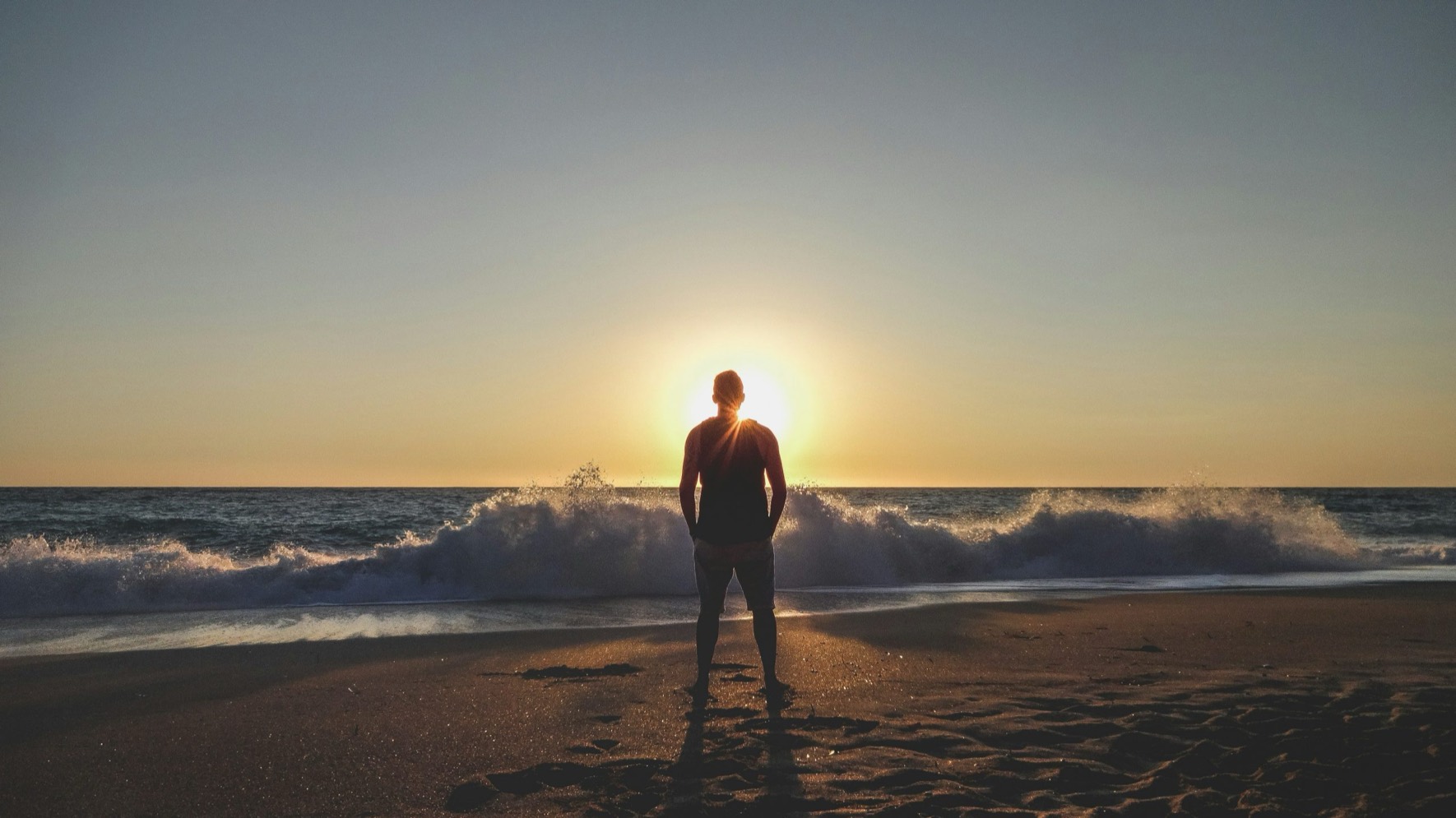 Ein Founder steht geerdet am Meer im Sonnenuntergang, ruhig und in seiner vollen Kraft